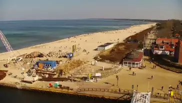 Widok z pylonu na plażę, latarnię morską i kanał portowy.