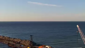 Widok z pylonu na plażę, latarnię morską i kanał portowy.