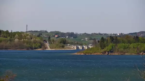 Widok z kamery ukazuje malowniczą linię brzegową, nad którą góruje charakterystyczna zapora w Świnnej Porębie