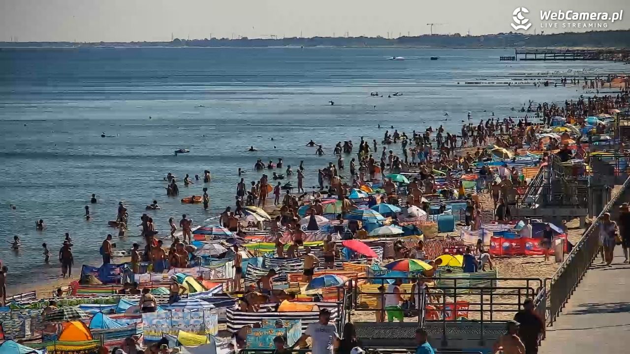 Kolorowe parawany, parasolki i tłumy wczasowiczów zażywających kąpieli słonecznych oraz morskich na plaży w Sarbinowie - lipiec 2022 rok