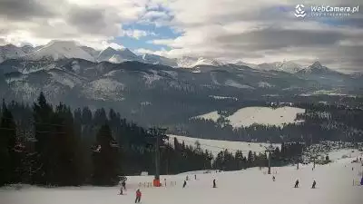 Szeroka trasa narciarska, wyciągi na stacji narciarskiej Małe Ciche. W tle panorama gór 